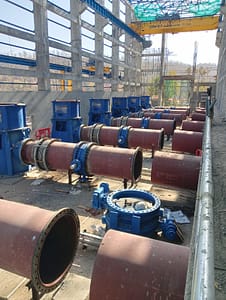 Large steel pipelines, valves, and fittings laid out at the site.