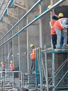 Construction workers securing scaffolding on a multi-story structure.
