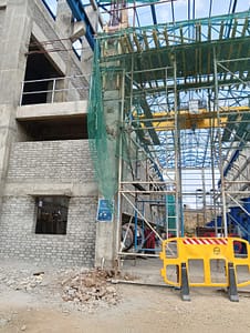 Tower crane and scaffolding at a partially completed pump house building.