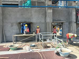 Workers arranging formwork and pouring concrete for foundational structures.
